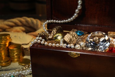 Photo of Wooden chest with treasures on floor, closeup