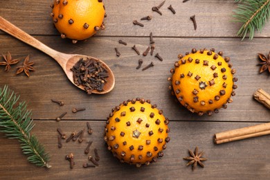 Photo of Pomander balls made of tangerines with cloves and fir branches on wooden table, flat lay