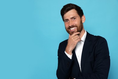 Photo of Portrait of smiling bearded man in suit on light blue background