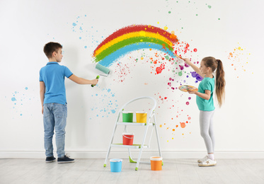 Image of Children drawing rainbow on white wall indoors