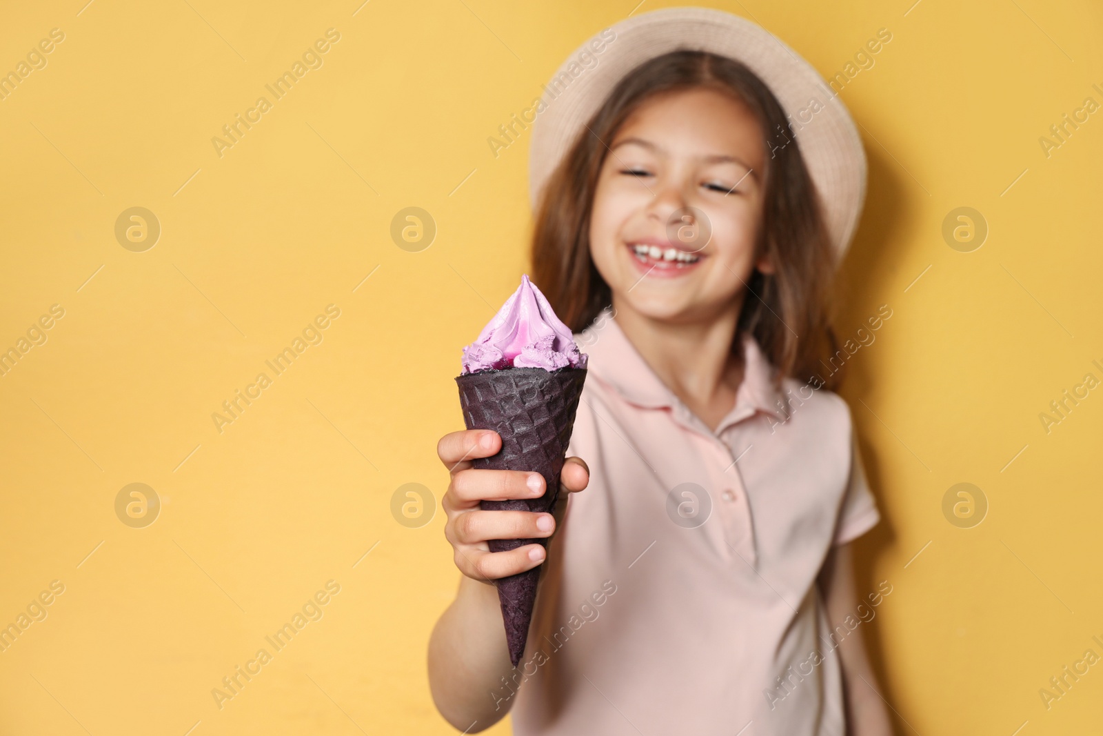 Photo of Adorable little girl with delicious ice cream against color background, space for text