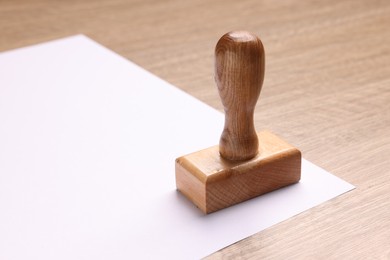 One stamp tool and sheet of paper on wooden table, closeup. Space for text