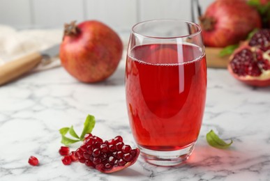 Photo of Tasty pomegranate juice in glass and fresh fruits on white marble table
