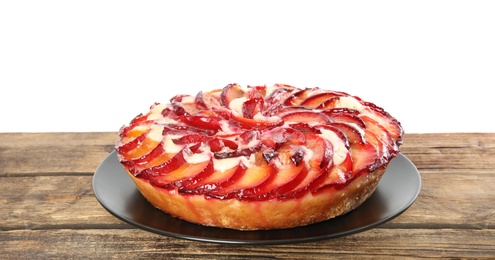 Delicious plum cake on wooden table against white background