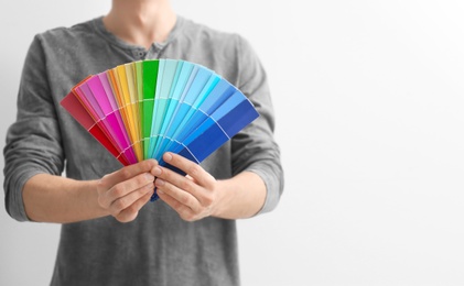 Photo of Male decorator holding color palette samples on white background