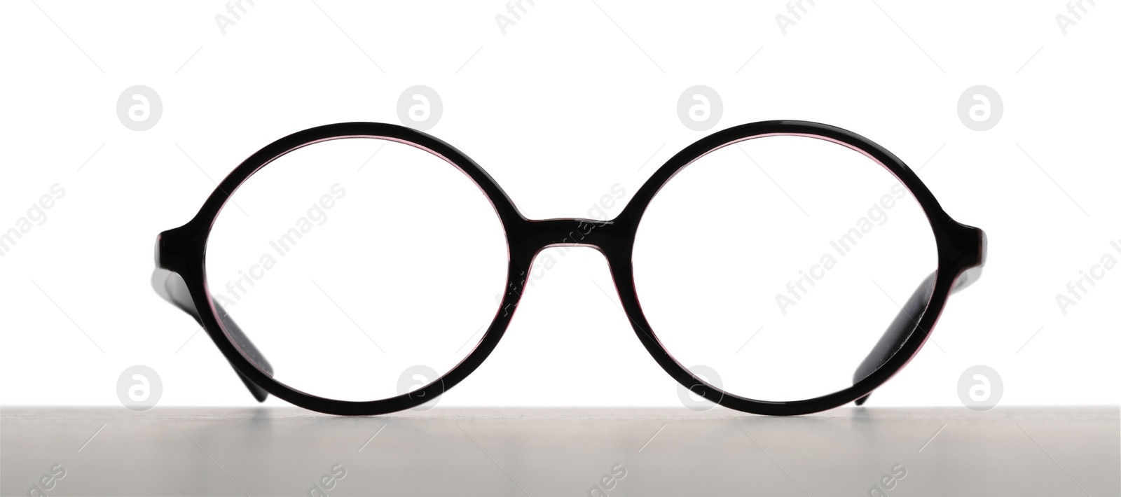 Photo of Stylish glasses with black frame on table against white background