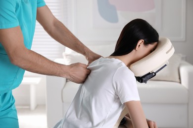 Woman receiving massage in modern chair indoors