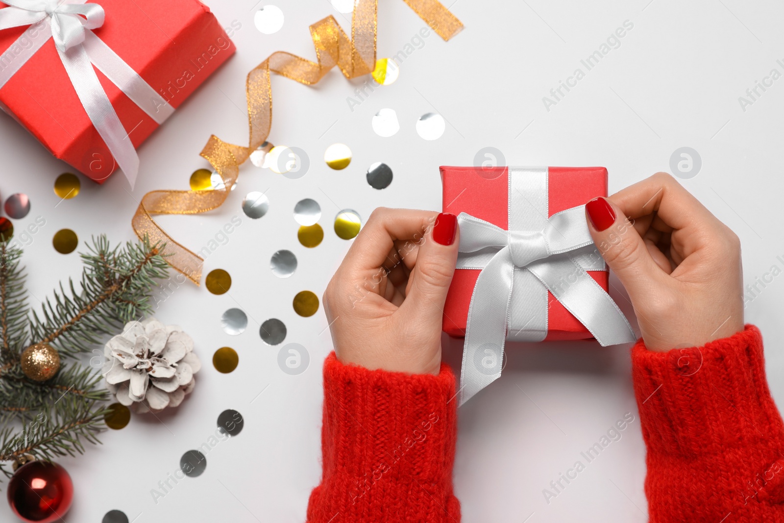 Photo of Woman with gift box near fir tree branch and Christmas decor on white background, top view