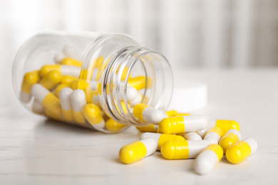 Photo of Bottle with vitamin pills on light table, closeup