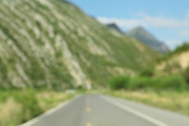 Blurred view of mountains and empty asphalt highway outdoors. Road trip