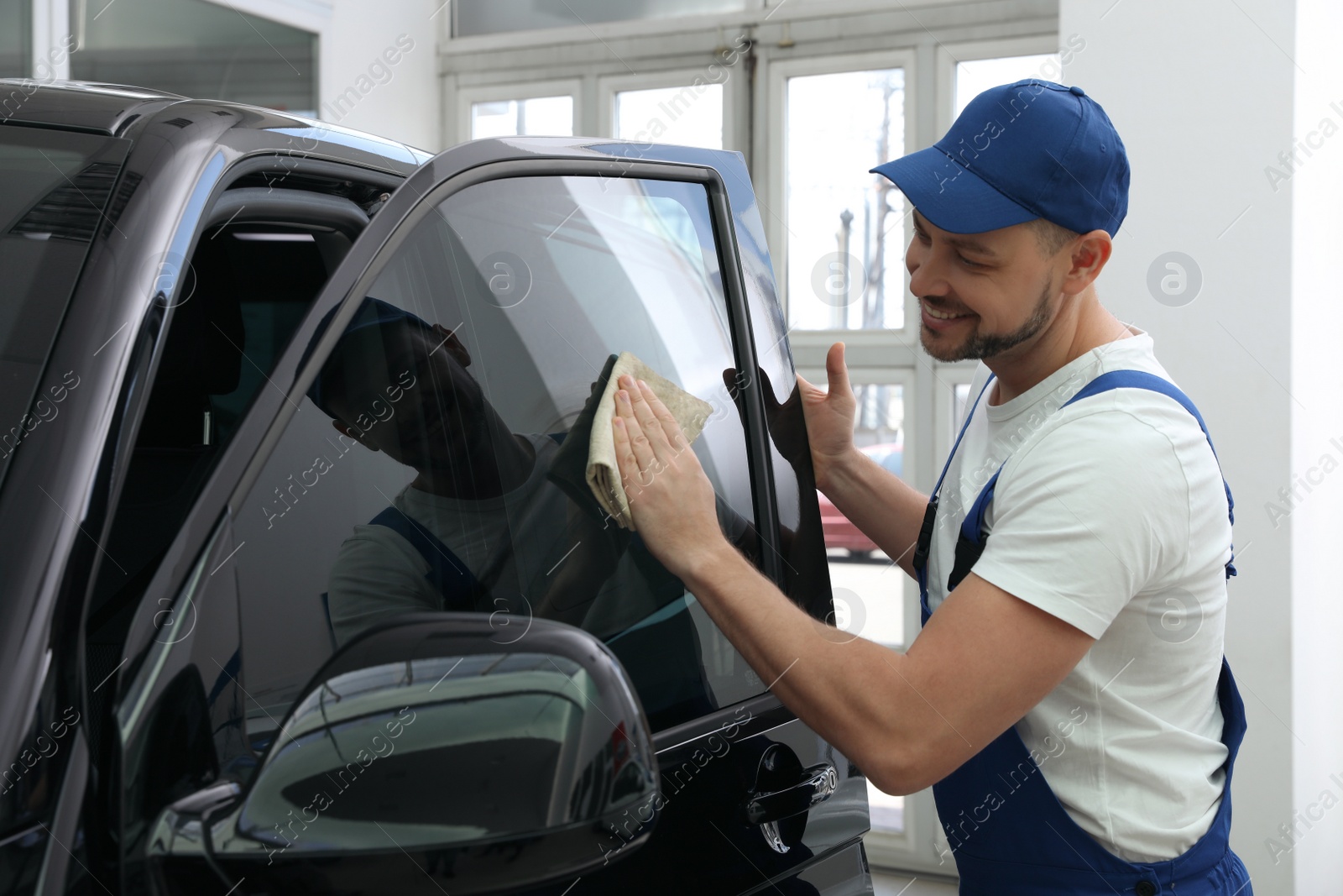 Photo of Worker tinting car window with foil in workshop