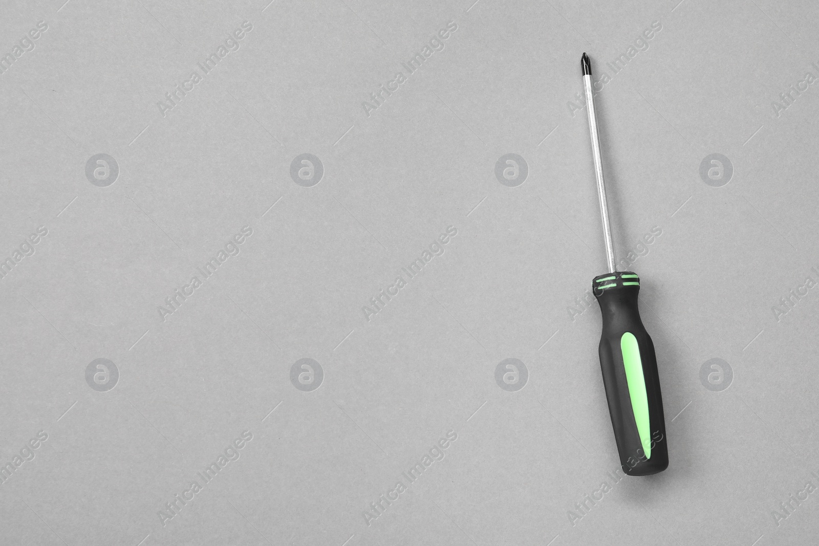 Photo of Screwdriver with black handle on grey background, top view. Space for text