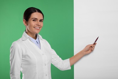 Photo of Ophthalmologist pointing at blank banner on green background, space for text