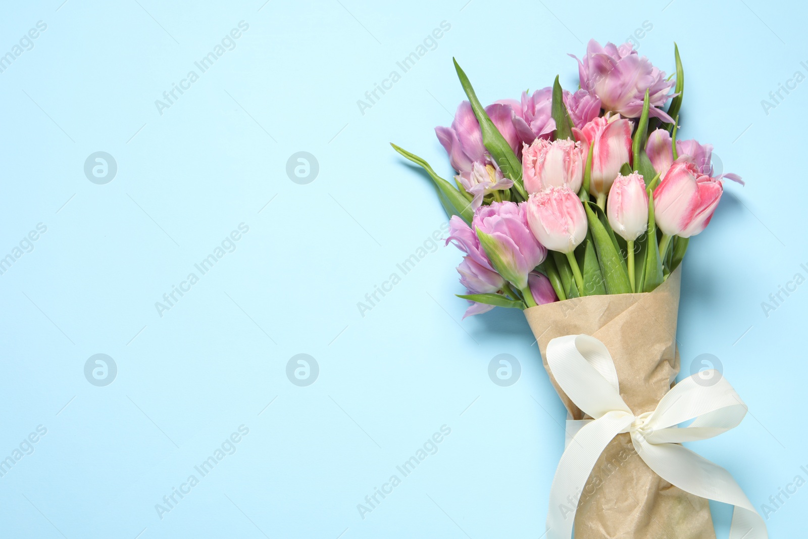 Photo of Beautiful bouquet of colorful tulip flowers on light blue background, top view. Space for text