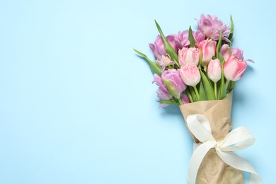 Beautiful bouquet of colorful tulip flowers on light blue background, top view. Space for text