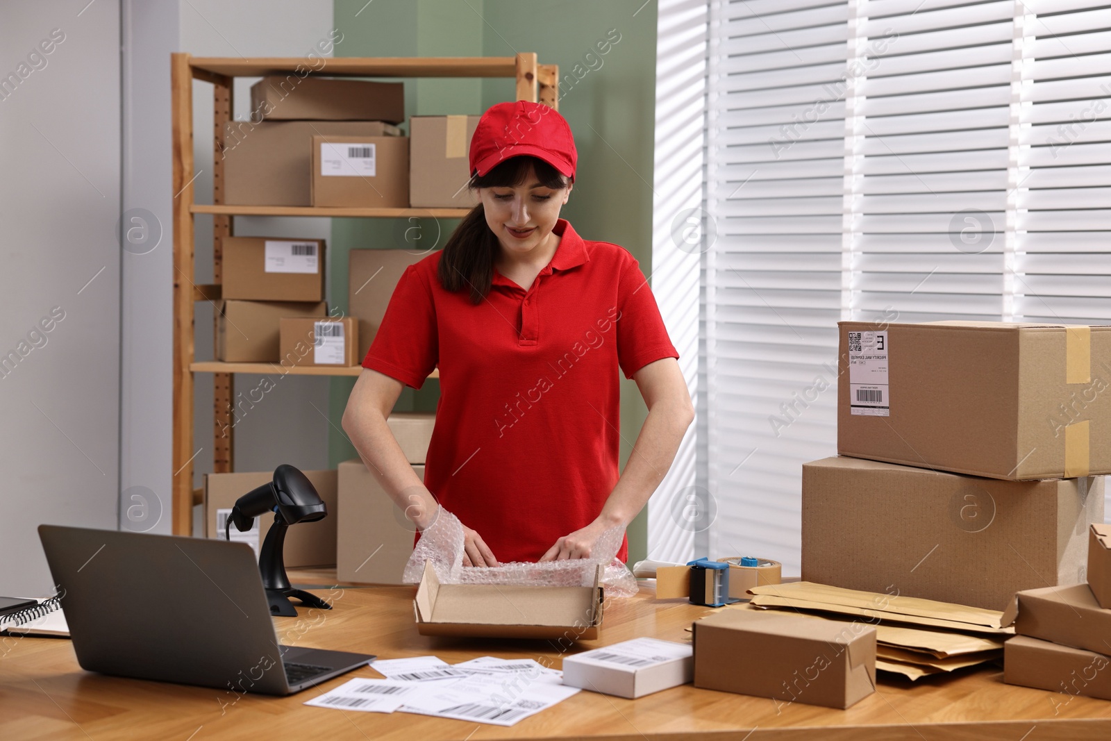 Photo of Post office worker packing parcel at wooden table indoors