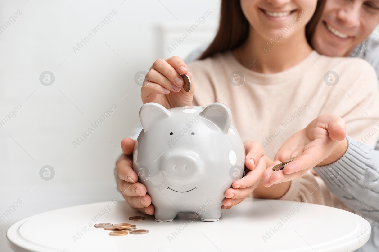 Photo of Couple with piggy bank at white table, closeup