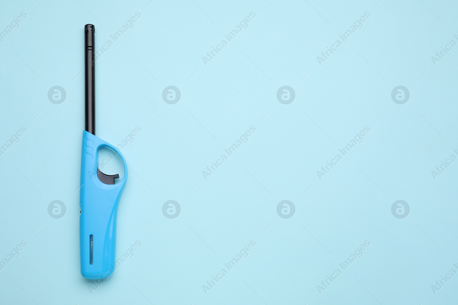 Photo of One gas lighter on light blue background, top view. Space for text