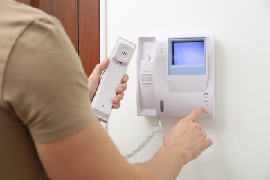 Photo of Man pressing button on intercom panel indoors, closeup