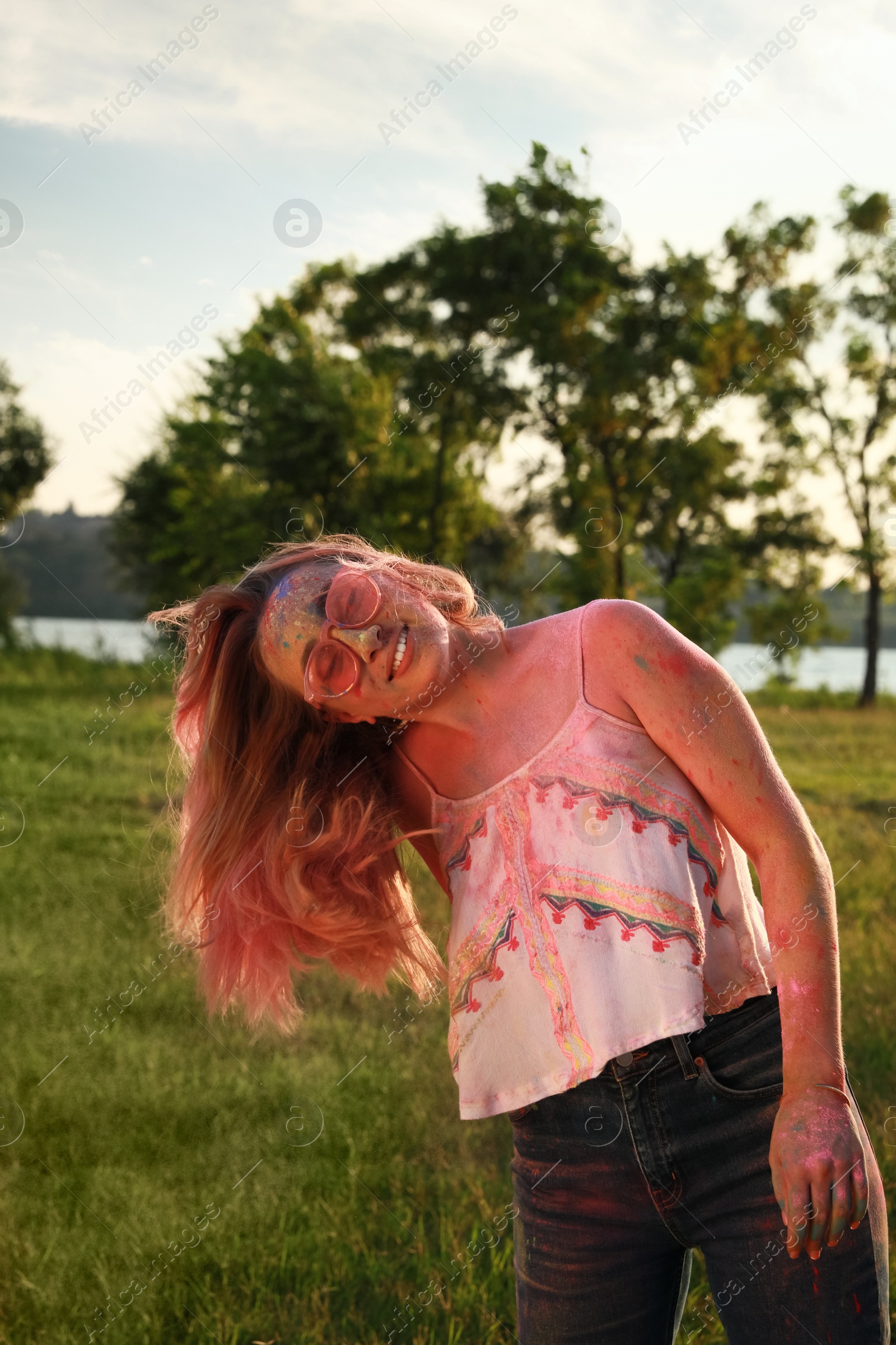 Photo of Happy woman covered with colorful powder dyes outdoors. Holi festival celebration