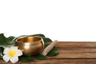 Photo of Golden singing bowl, mallet, leaf and flower on wooden table against white background, space for text