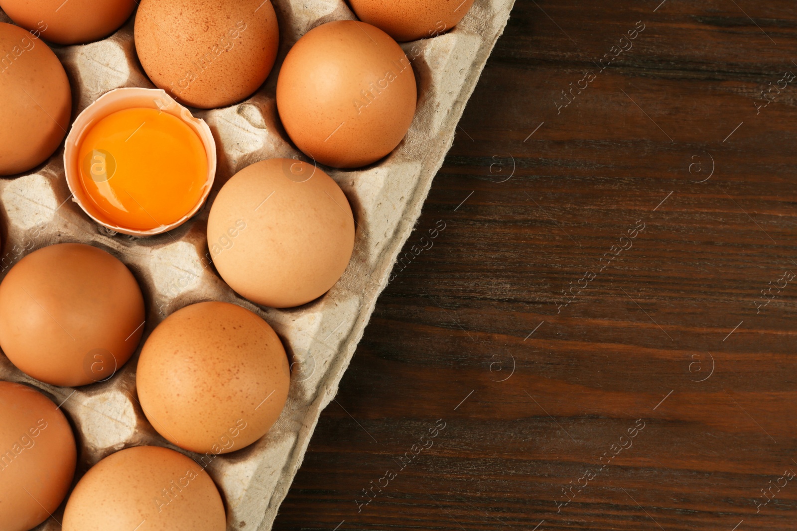 Photo of Raw chicken eggs on wooden table, top view. Space for text