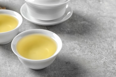 Photo of Cups of freshly brewed oolong tea on grey table. Space for text