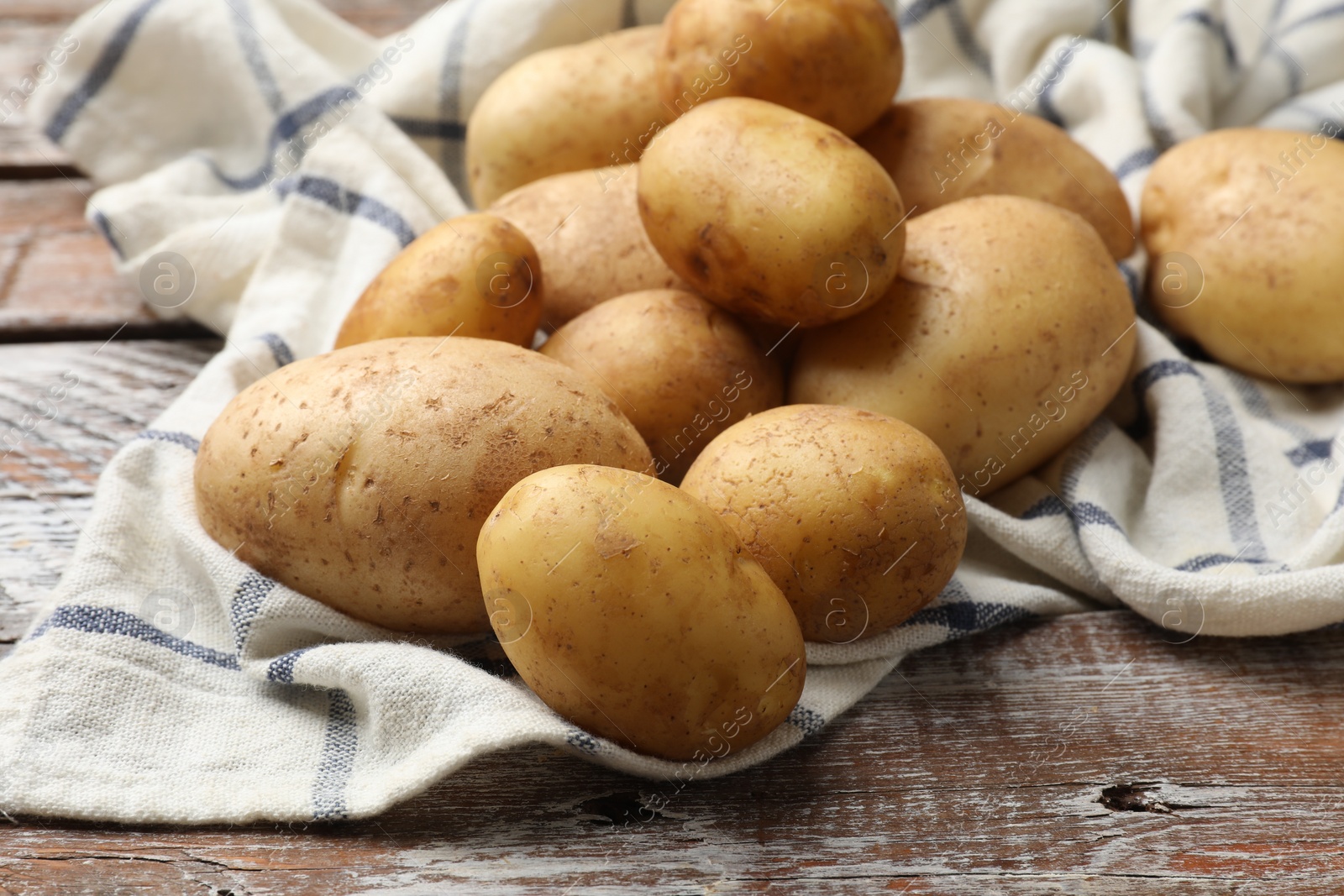 Photo of Raw fresh potatoes and napkin on wooden table