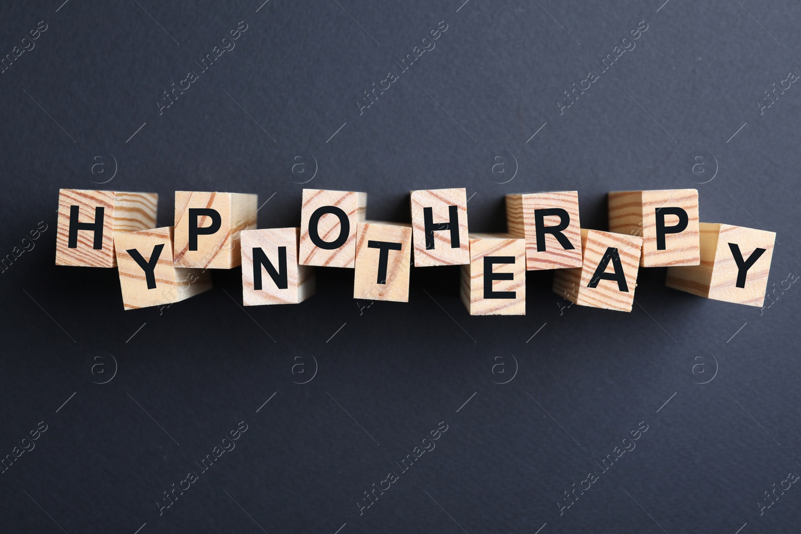 Photo of Wooden blocks with word HYPNOTHERAPY on black background, flat lay