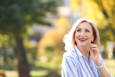 Portrait of happy mature woman in park on sunny day