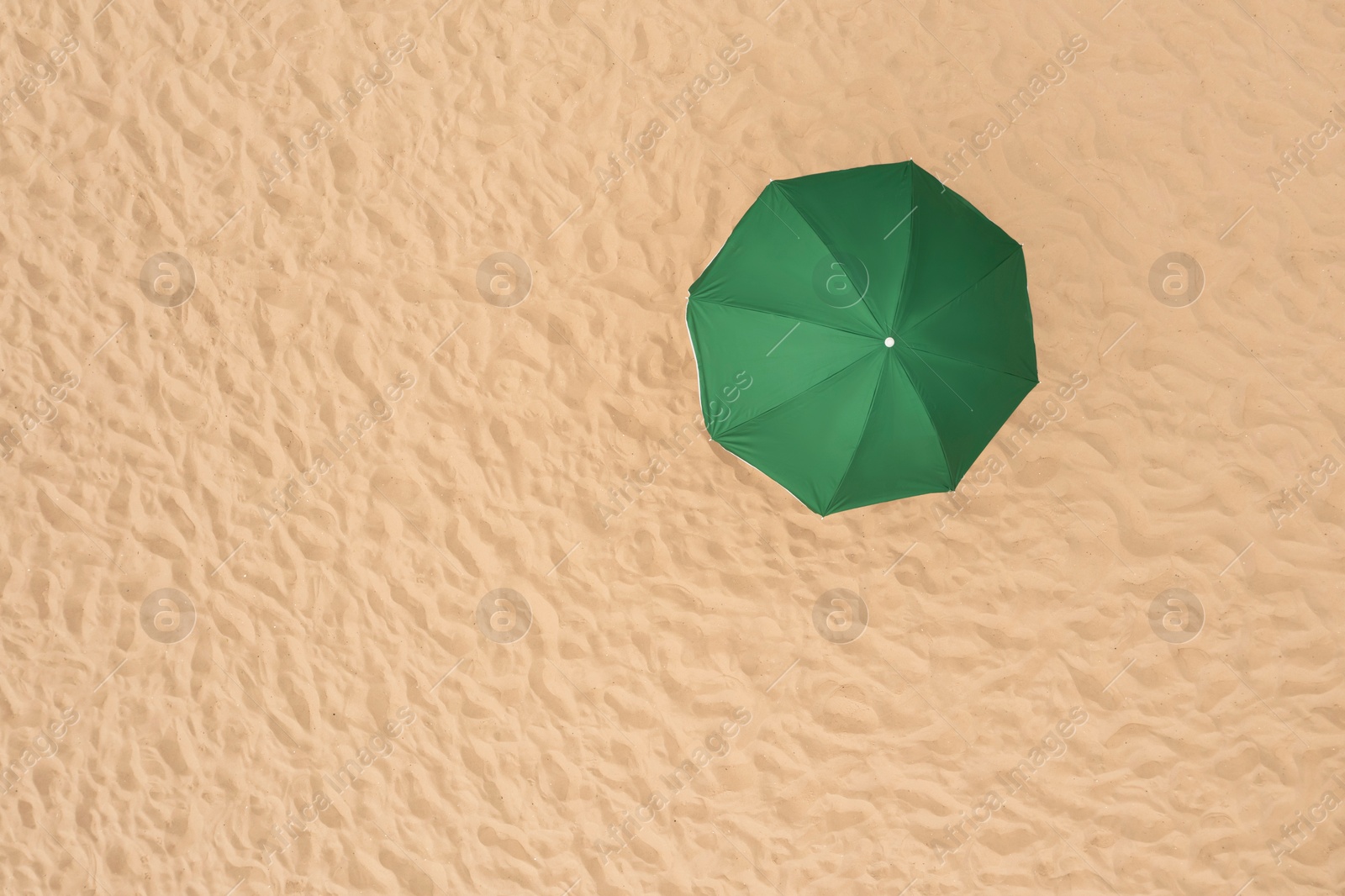 Image of Green beach umbrella on sandy coast, aerial view. Space for text