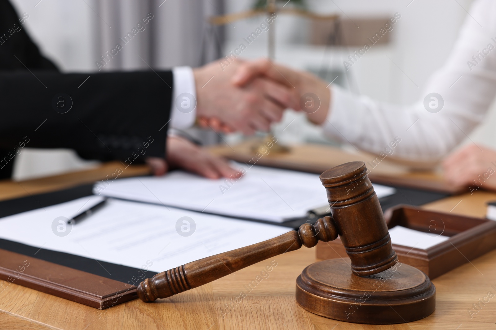 Photo of Lawyer shaking hands with client in office, focus on gavel