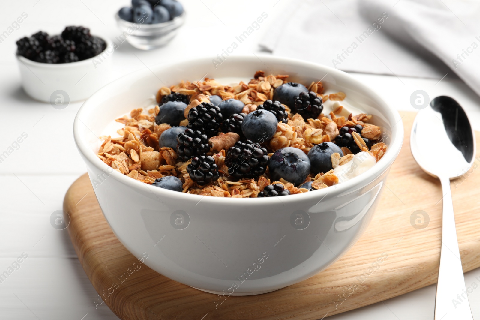 Photo of Bowl of healthy muesli served with berries on white wooden table, closeup