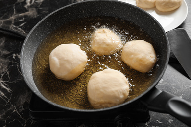 Photo of Cooking delicious donuts in hot oil, closeup