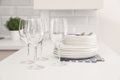 Photo of Stack of clean dishes and glasses on table in kitchen