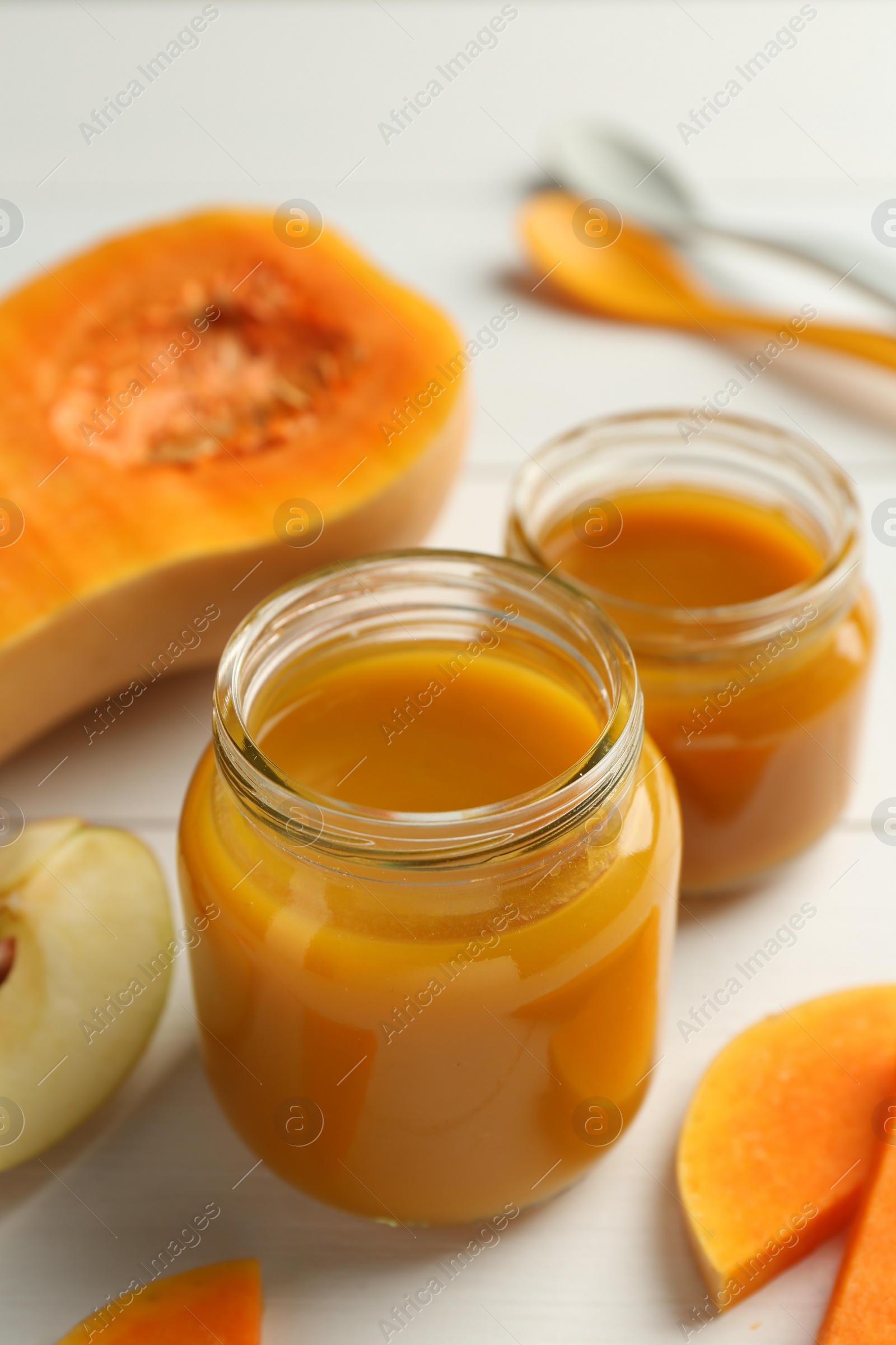 Photo of Tasty baby food in jars and ingredients on white table, closeup