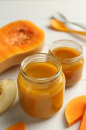 Tasty baby food in jars and ingredients on white table, closeup