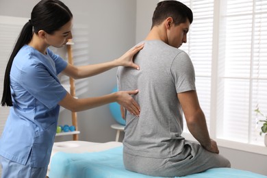 Orthopedist examining man's back in clinic. Scoliosis treatment