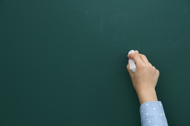 Photo of Little child writing on chalkboard, closeup. Space for text