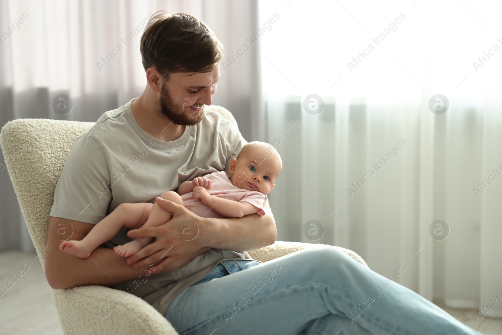 Photo of Father with his cute baby in armchair at home, space for text