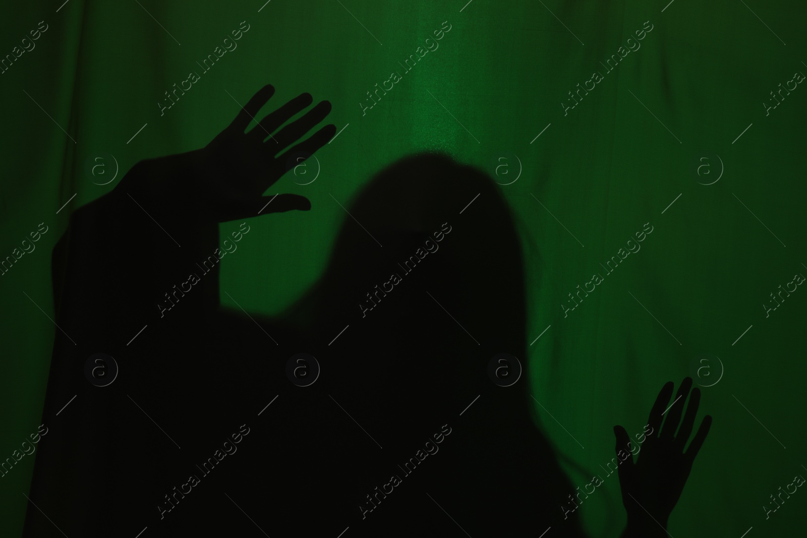 Photo of Silhouette of creepy ghost behind dark green cloth