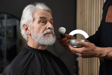 Photo of Professional barber working with client's mustache in barbershop