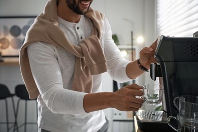 Photo of Man preparing fresh aromatic coffee with modern machine in office, closeup