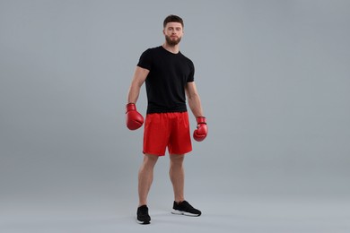 Photo of Man in boxing gloves on grey background