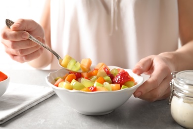 Photo of Woman with bowl of fresh fruit salad, closeup