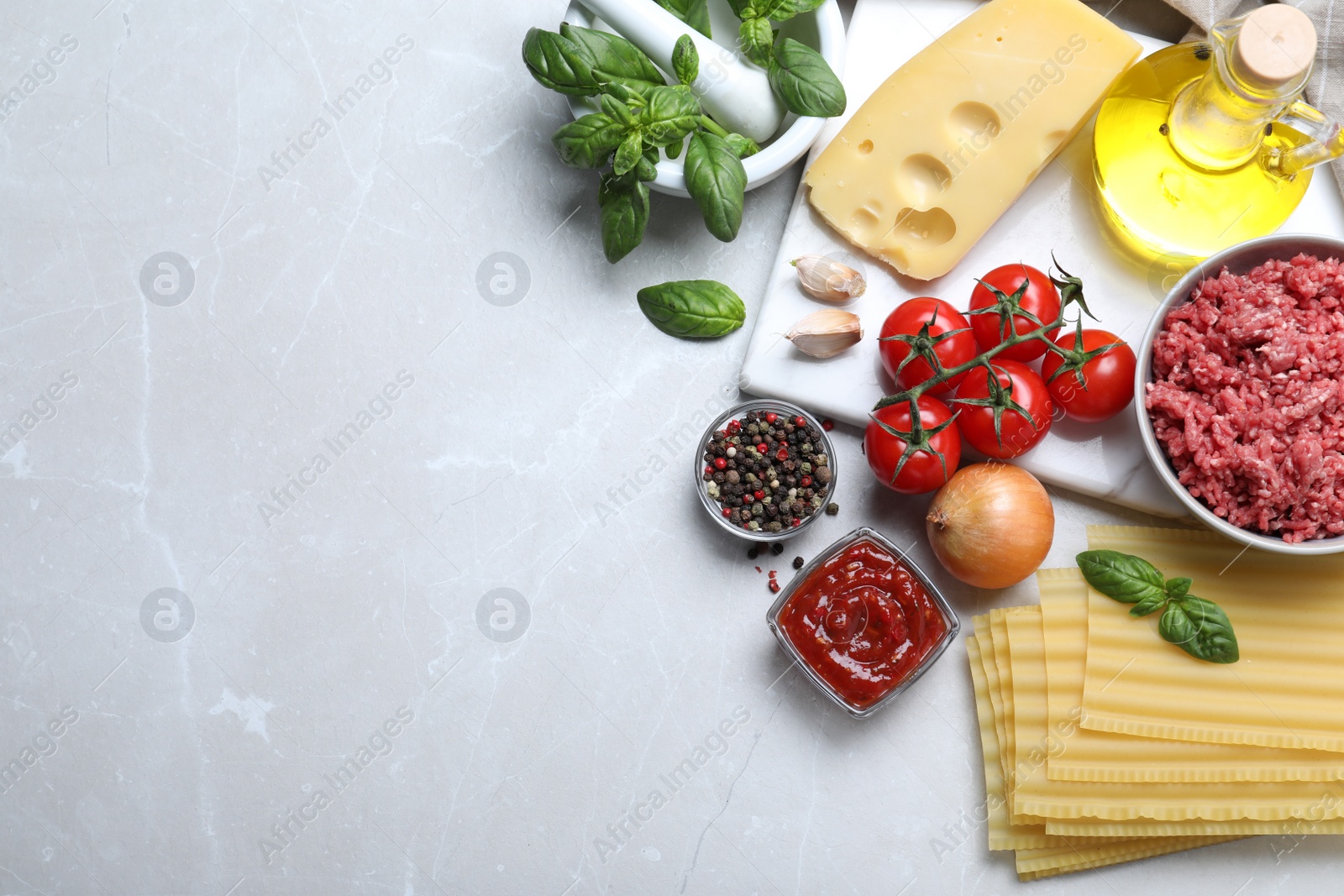 Photo of Fresh lasagna ingredients on light grey marble table, flat lay. Space for text