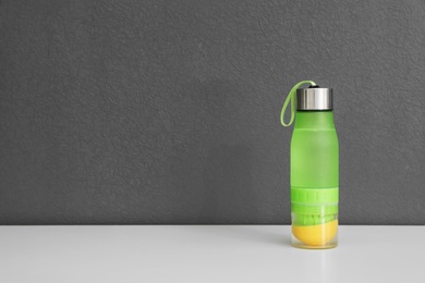 Photo of Sport bottle with lemon water on gray background. Space for text