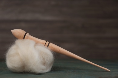 Soft white wool and spindle on blue wooden table. Space for text