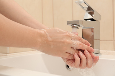 Photo of Woman washing hands with antiseptic soap in bathroom, closeup