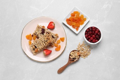 Tasty granola bars and ingredients on light marble table, flat lay